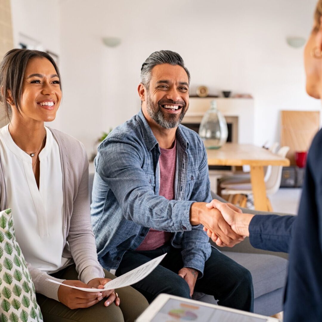 A man shaking hands with another person in front of two women.